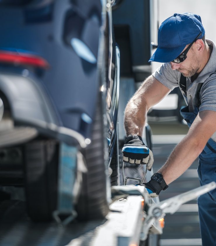Towing Company Worker Securing Vehicle on the Truck Platform
